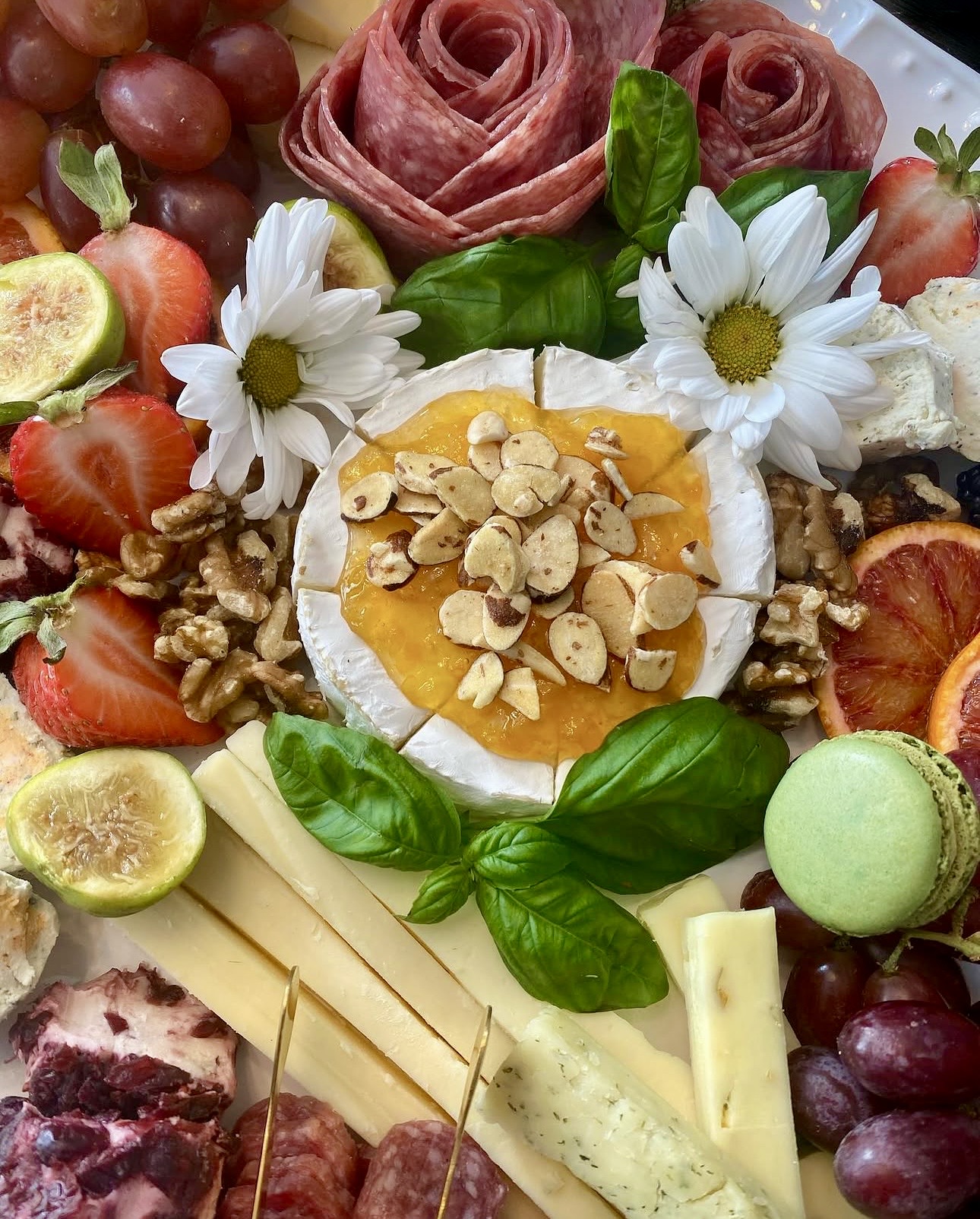 Brie with honey and nuts surrounded by salami roses and fresh fruit